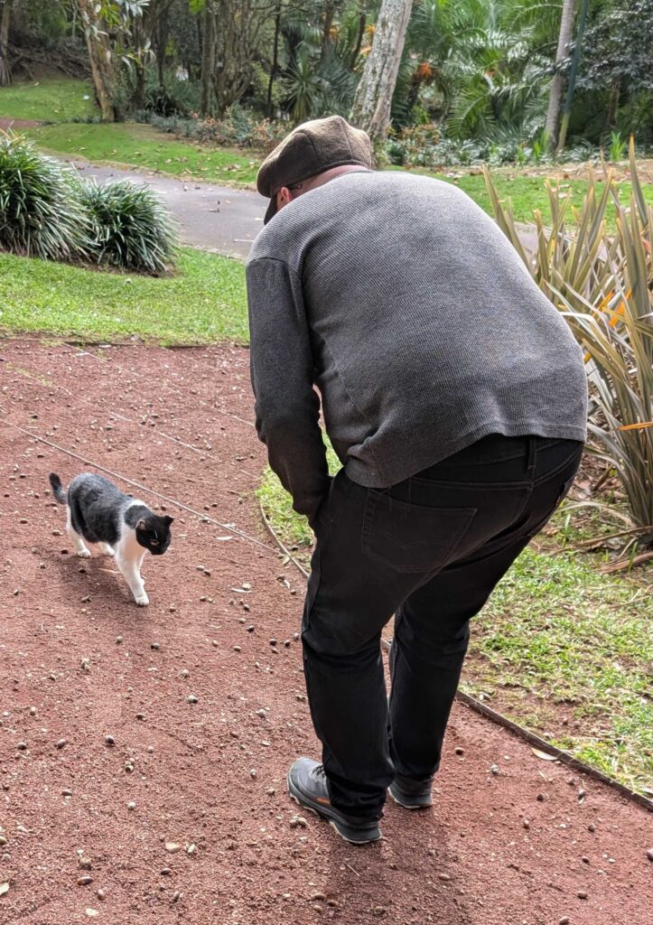 The author's spouse leaning over to greet a friendly tuxedo cat.