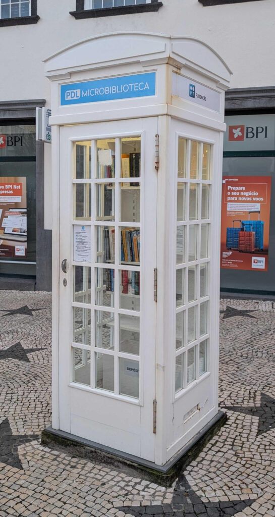 A white phone booth, similar to the classic red ones found in the UK.  This one has been converted into a tiny library.